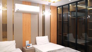 A hotel room with two beds, a wardrobe, and an air conditioning unit. - Premium Swiss Residence Mohandessin (Cairo)