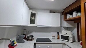 A compact kitchen with white cabinets, a stainless steel sink, a microwave, a toaster, and a small oven. - Fantastic apartment in La Manga Club. Swimming pool, restaurants, pubs, golf beach (Cartagena)