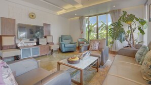 Una sala de estar moderna con sofá, sillones, una mesa de centro y televisión.