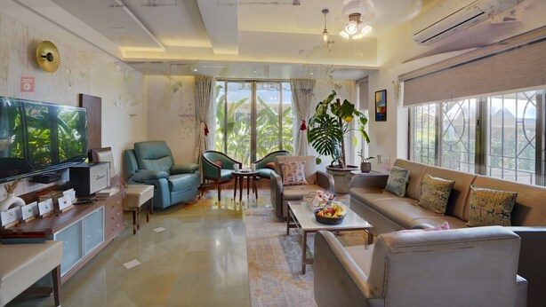 Un salón amplio con un televisor grande, asientos cómodos, una mesa de centro y ventanas grandes que ofrecen vistas al exterior.