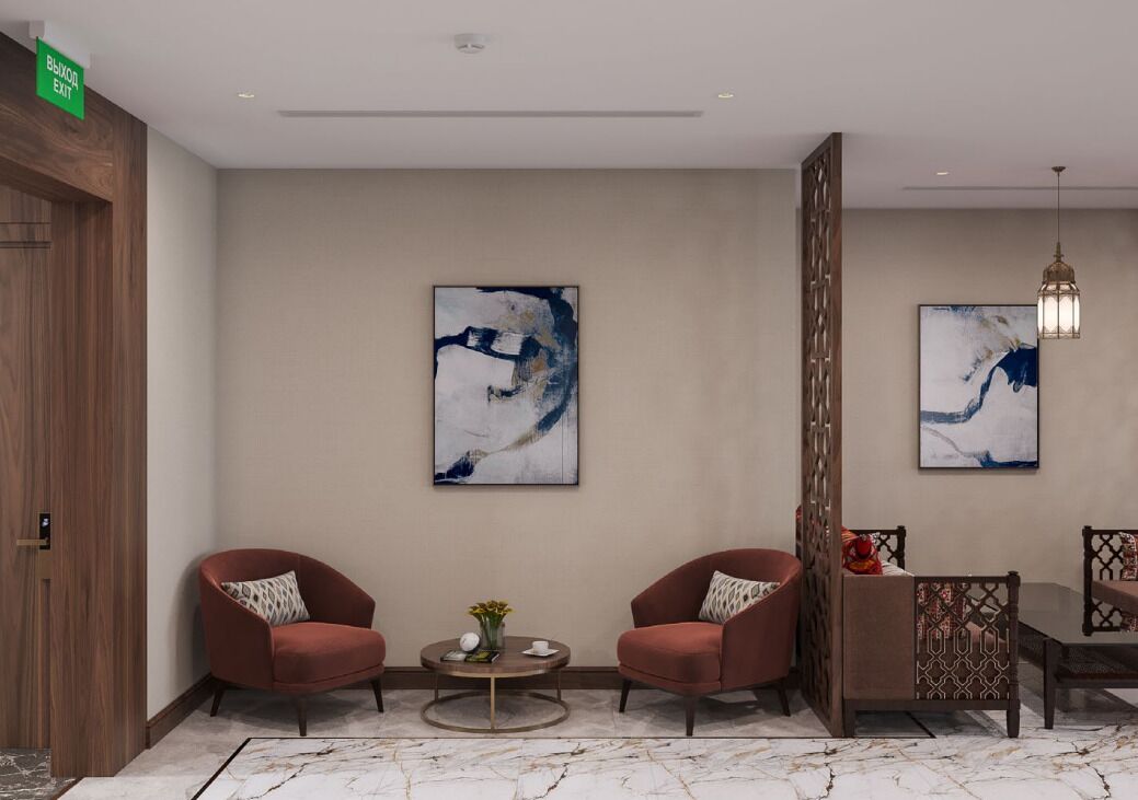 A modern lobby with two red armchairs, a round coffee table, and abstract paintings on the walls.