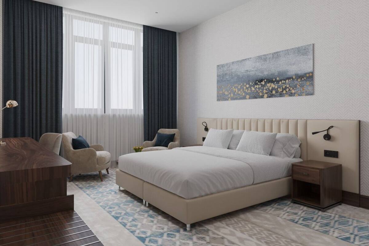 A modern bedroom with a large bed, a bedside table, a chair, and a desk.
