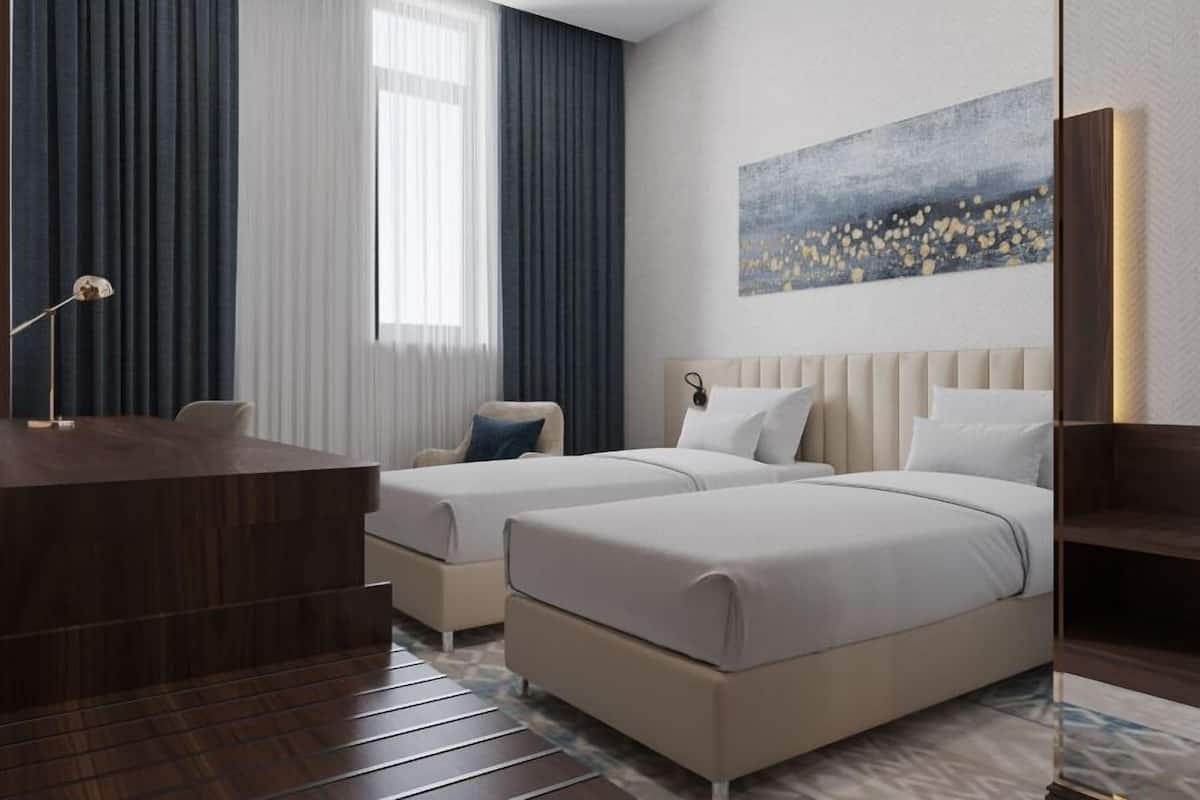 A hotel room with two beds, a desk, and a large window with curtains.