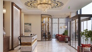 A hotel lobby with a reception desk, a chandelier, a glass partition, and seating area with plants. - Surxondaryo Hotel (Tashkent)