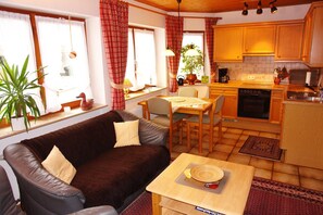 Un salon confortable avec un canapé, une table à manger et une cuisine en arrière-plan.
