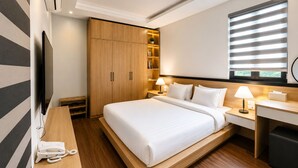 A modern hotel room with a large bed, bedside lamps, a desk, a wardrobe, and a TV.