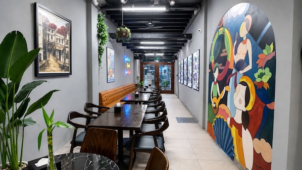 Un amplio comedor con mesas y sillas, un banco y un mural colorido en la pared.