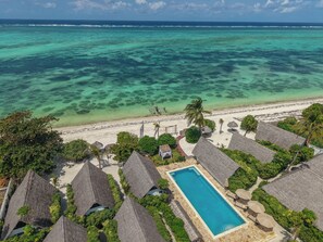 A resort with thatched-roof bungalows, a swimming pool, and a beach with clear turquoise waters. - Juana Ocean Villas (Makunduchi)