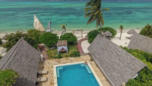 A pool area with a clear view of the ocean and beach huts.