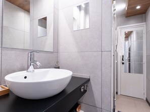 A modern bathroom with a white sink, black countertop, and a mirror above it.