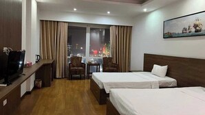 Camera d'albergo con due letti, televisione, scrivania e vista sulla città di notte.