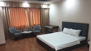 Una camera d'albergo con un letto, due poltrone, un tavolino e una scrivania.