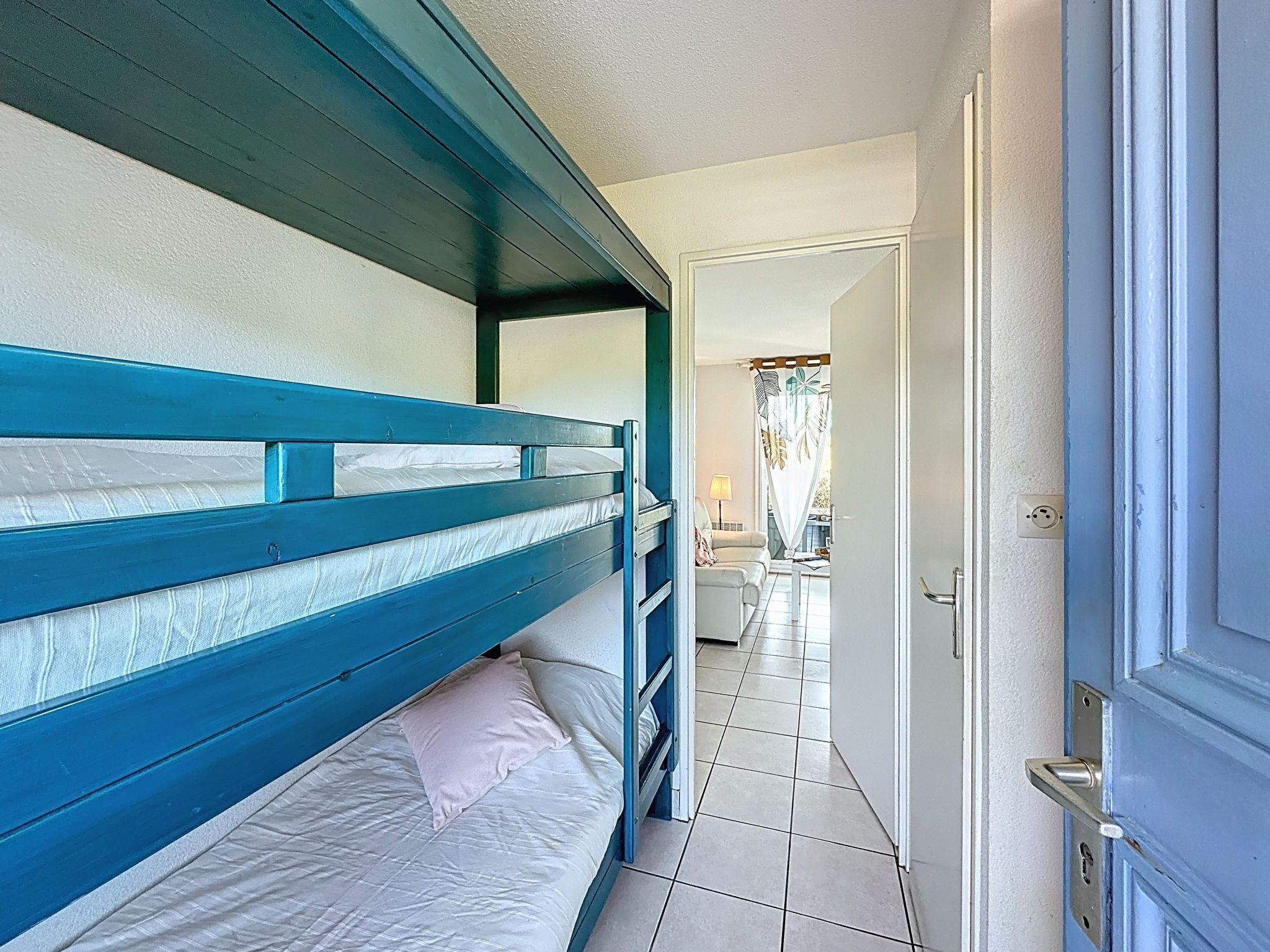 Quarto com beliche e vista para uma sala de estar.