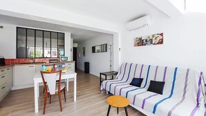 A modern living space with a dining area, a sofa, and a kitchen.