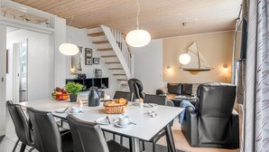 A modern dining area with a white table, black chairs, and a staircase leading to a loft. - "Lucjan" - 800m from the sea by Interhome (Vejers Strand)