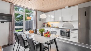 A modern kitchen with white cabinets, a stainless steel refrigerator, and a dining area with a glass table and black chairs. - "Lucjan" - 800m from the sea by Interhome (Vejers Strand)
