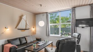 A modern living room with a black leather sofa, a coffee table, a TV, and a sailboat decoration on the wall. - "Lucjan" - 800m from the sea by Interhome (Vejers Strand)