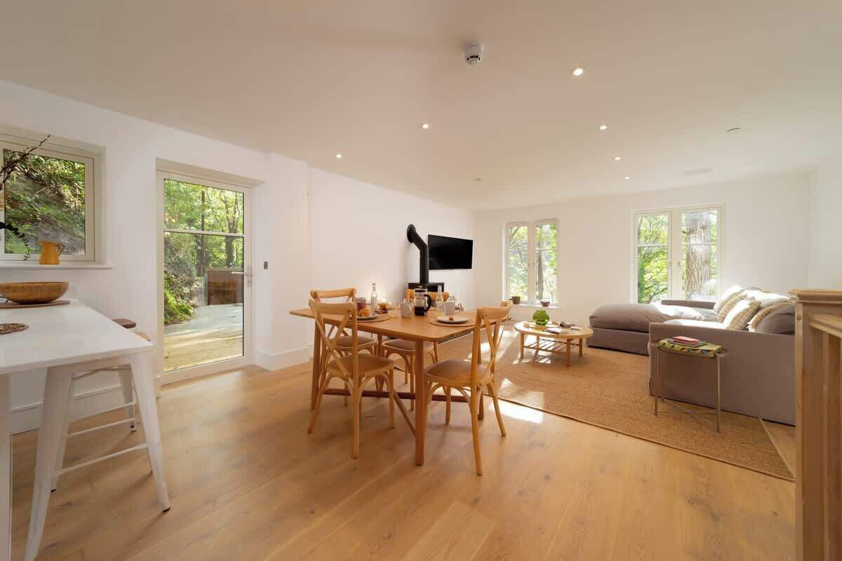 A spacious living area with a dining table and chairs, a sofa, and a television.