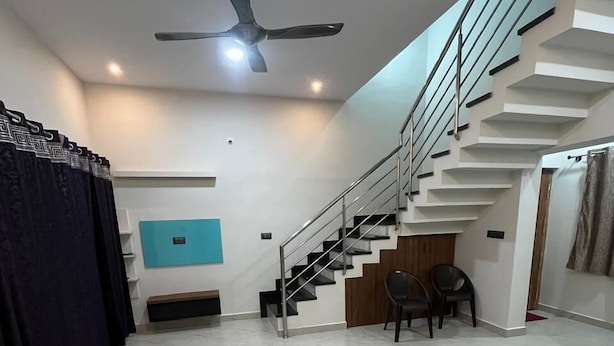 A spacious living area with a modern staircase, a ceiling fan, and a blue accent wall.