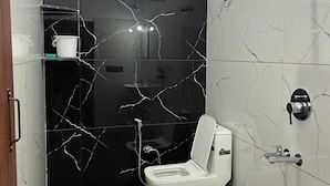A bathroom with a toilet, a shower, and a sink.