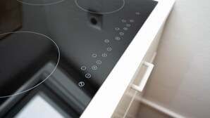 A modern kitchen with a black induction cooktop and a white handle. - Guesthouse Elena Apartment 13 (Kassel)