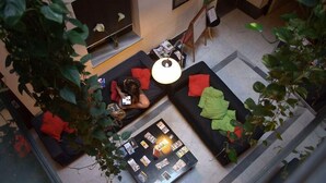 A modern living area with a sofa, a coffee table with magazines, and a TV. - Joy Setas Coworking (Seville)