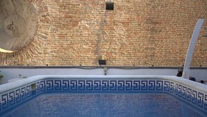 Una piscina con borde de azulejos y un muro de ladrillo al fondo.