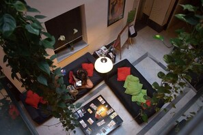 A modern living area with a sofa, a coffee table with magazines, and a TV. - Joy Setas Coworking (Seville)