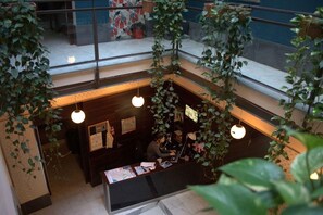 A reception area with a desk, computer, and hanging plants. - Joy Setas Coworking (Seville)