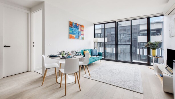 A modern living room with a dining area, a teal sofa, and a large window with a city view. - Luxury Living in Heart of South Yarra near Jam Factory, Prahran Market Chapel St (South Yarra)