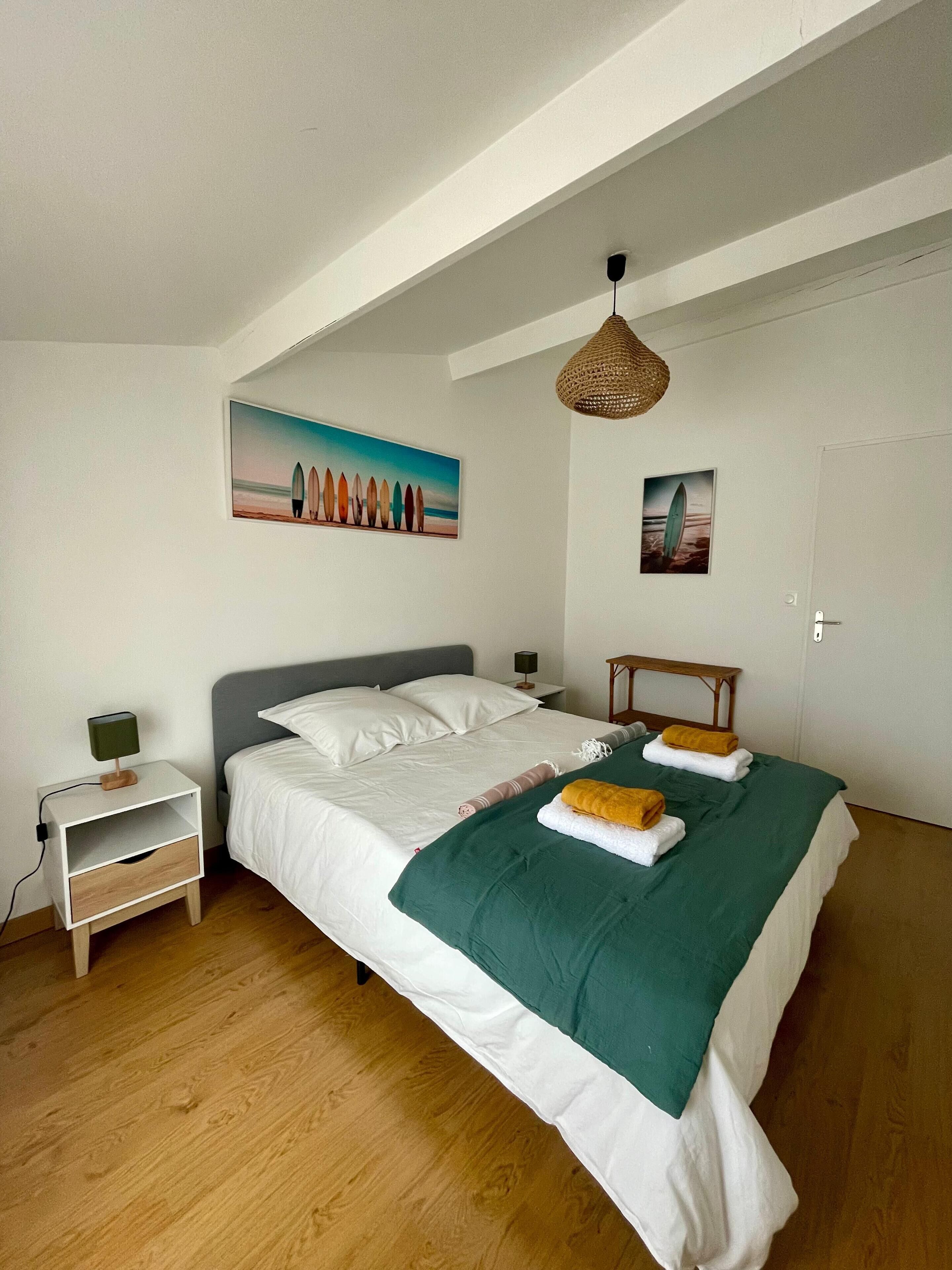 A bedroom with a bed, a nightstand, a lamp, and two paintings on the wall.