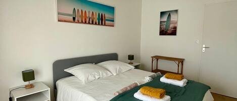 A bedroom with a bed, a nightstand, a lamp, and two paintings on the wall.