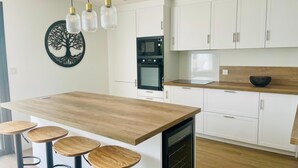 Eine moderne Küche mit weißen Schränken, einer Holz-Kochinsel mit Hockern und Pendelleuchten.