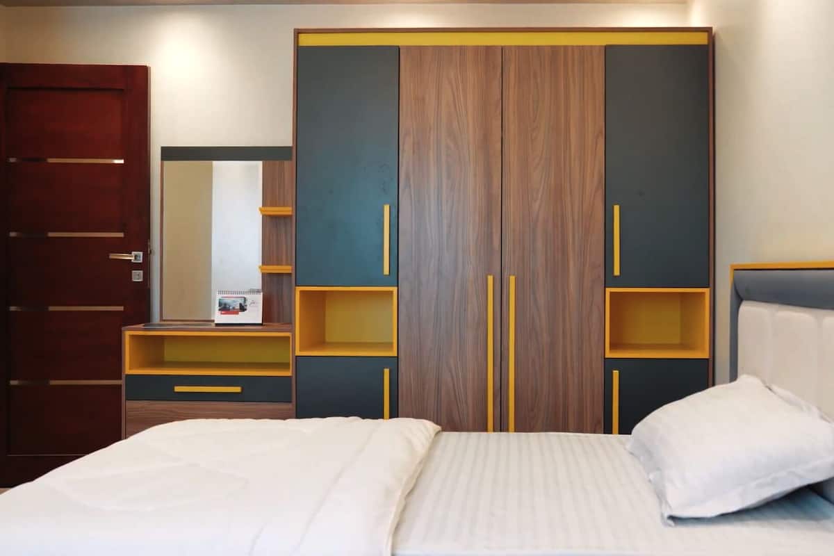 A bedroom with a bed, a wardrobe, a mirror, and a dresser.