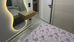 A modern bedroom with a large bed, a built-in mirror, and a bedside table. - Cozy 2-bedroom chalet in amazing El-Alamein - golf porto marina with AC (El-Alamein)