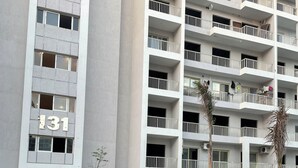 A multi-story residential building with balconies, a number '131' sign, and a paved courtyard with plants and a parked motorcycle. - Cozy 2-bedroom chalet in amazing El-Alamein - golf porto marina with AC (El-Alamein)
