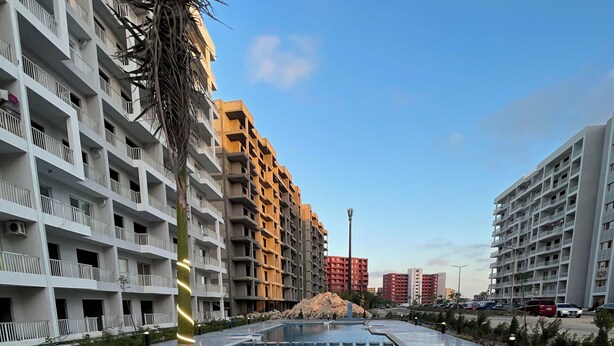 A residential area with multi-story buildings, a swimming pool, and a palm tree. - Cozy 2-bedroom chalet in amazing El-Alamein - golf porto marina with AC (El-Alamein)