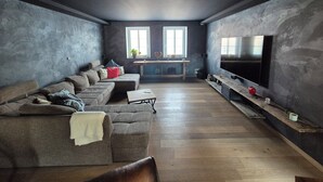 Ein modernes Wohnzimmer mit einer Eckcouch, einem Fernseher und Holzboden.