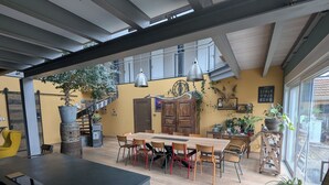 Ein geräumiger Essbereich mit Holztisch und -stühlen, einer Treppe und einem großen Fenster für natürliches Licht.