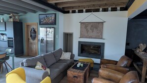 Ein geräumiges Wohnzimmer mit Holzboden, einem Kamin und einem Essbereich mit Tisch und Stühlen.