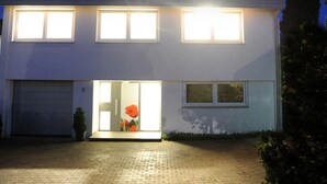 A modern two-story house with a garage, a driveway, and a well-lit entrance.