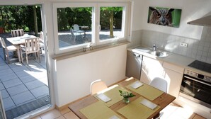 A compact kitchen with a dining area, a window with a view of the outdoors, and a wall-mounted picture.