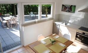 Cocina compacta con comedor, ventana con vistas al exterior y un cuadro colgado en la pared.