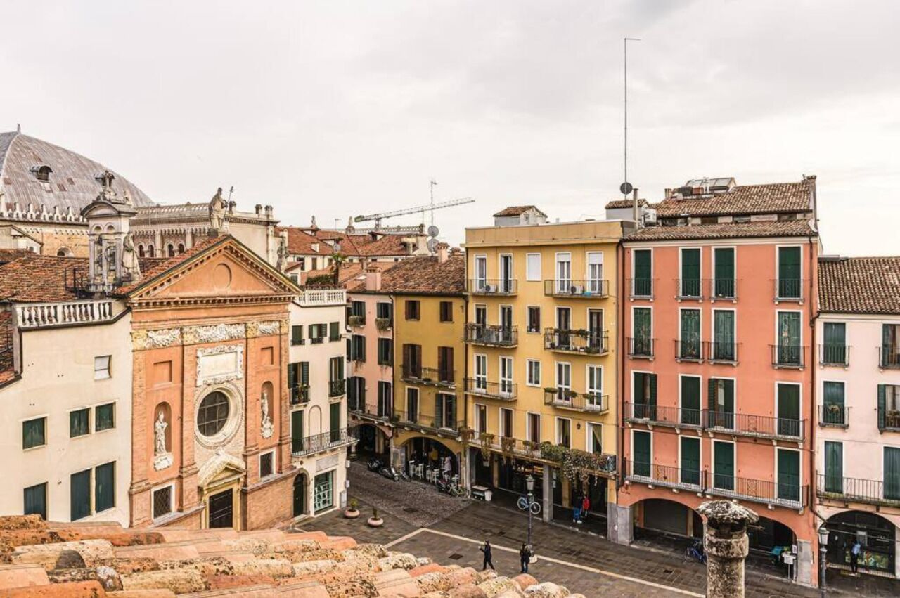 A street view of historic buildings with balconies and a dome in the background.