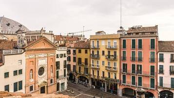 A street view of historic buildings with balconies and a dome in the background.