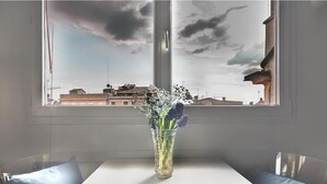 A room with a large window, a white table, and a vase with flowers. - enJoy Home - Attic Room in Lords' Square (Padova)