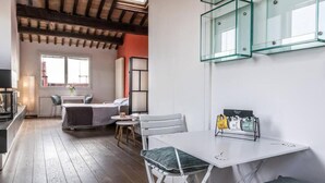 A modern room with a wooden floor, white furniture, a glass cabinet, and a view of the outside. - enJoy Home - Attic Room in Lords' Square (Padova)