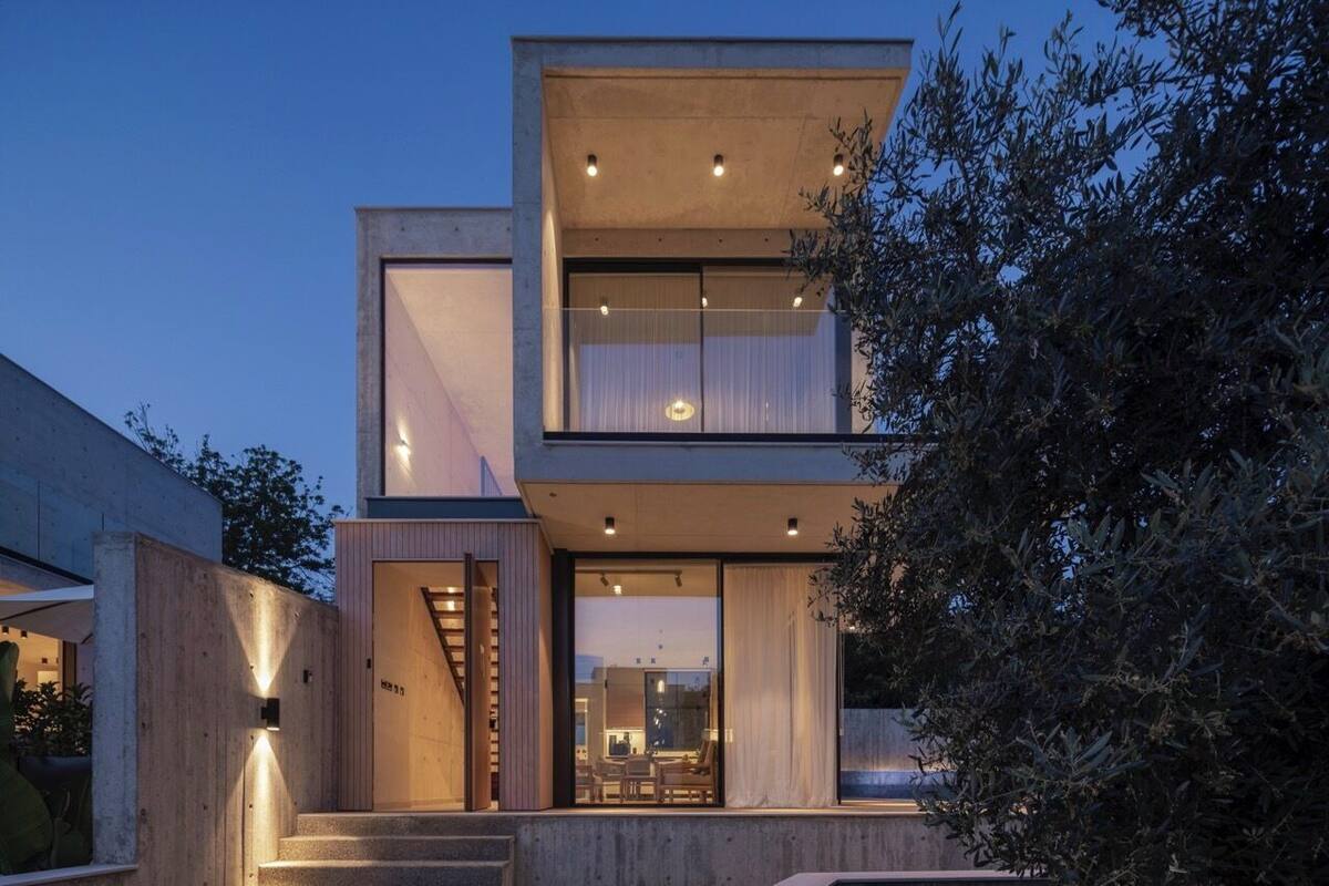 A modern two-story building with a concrete facade, large windows, and a visible staircase leading to the entrance.