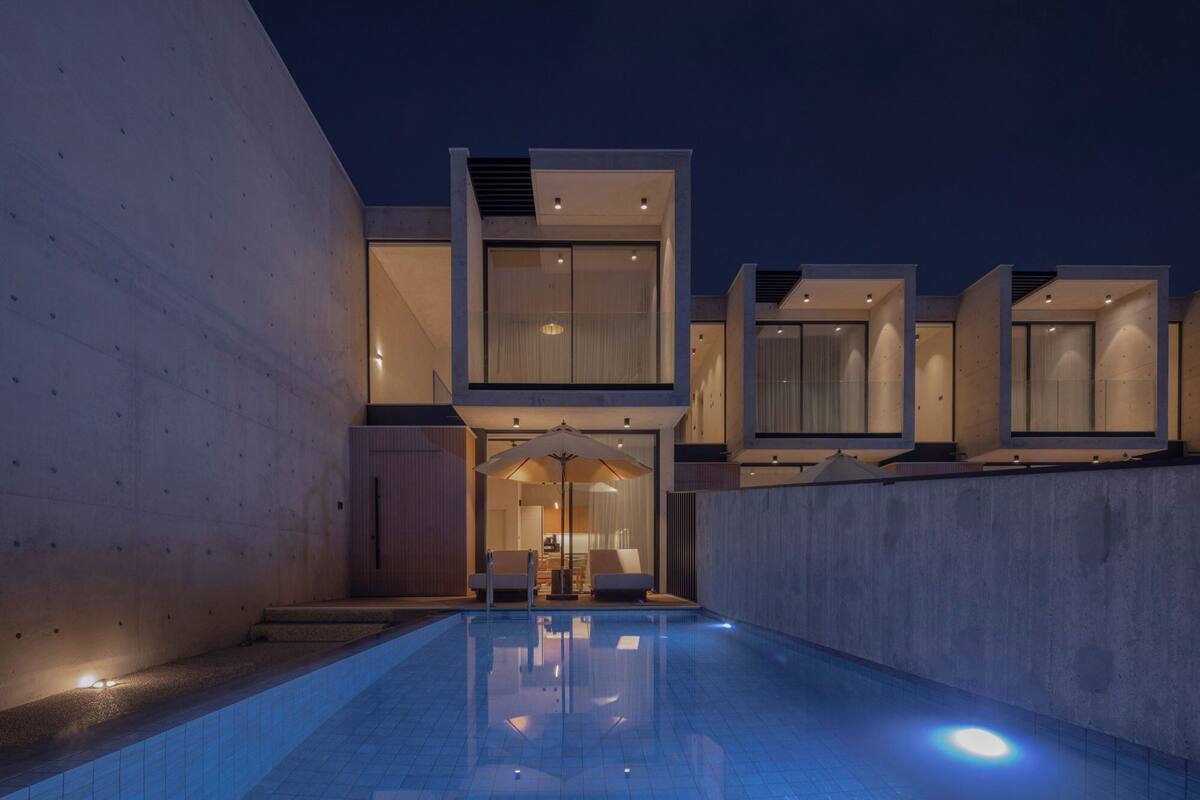 A modern building with a pool, large windows, and a minimalist design.