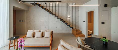 Et moderne interiør med trappe, sofa, spisebord og en plante.
